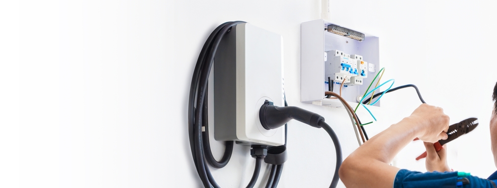 Electrician installing an EV charger while checking hidden installation costs