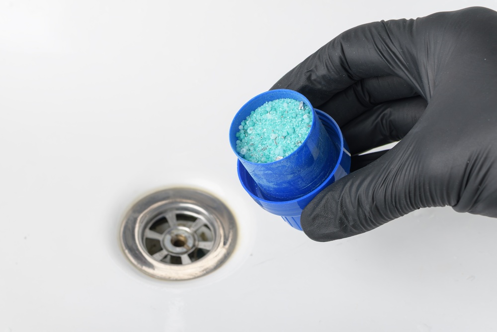 Homeowner attempting DIY drain cleaning and facing plumbing risks